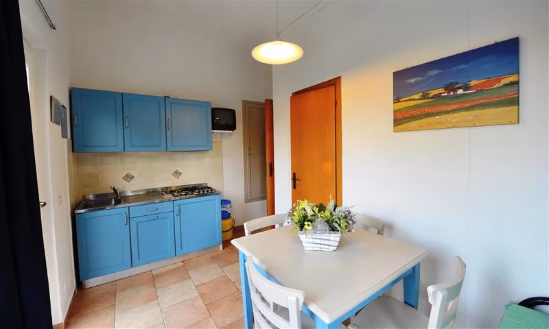 Keuken met lichtblauwe kastjes en een witte eettafel met bloemen in een appartement op Camping Bella Italia