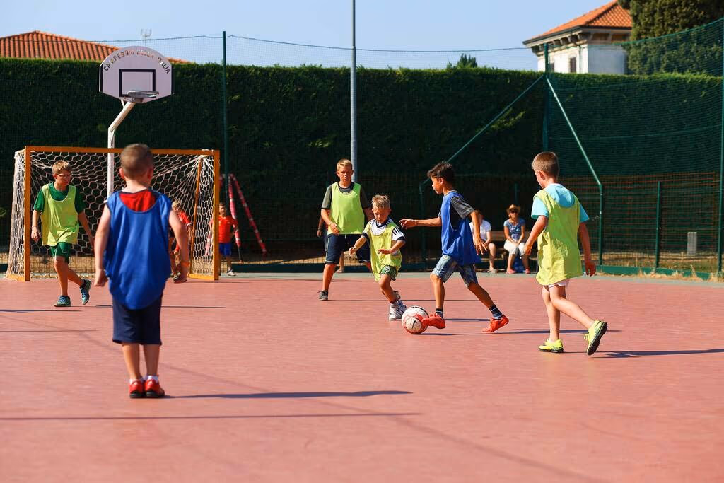 Jongeren spelen basketbal op het sportveld van Camping Bella Italia in Peschiera del Garda
