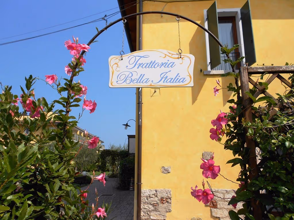 Decoratief bord van restaurant Le Terrazze sul Lago aan een gele gevel op Camping Bella Italia
