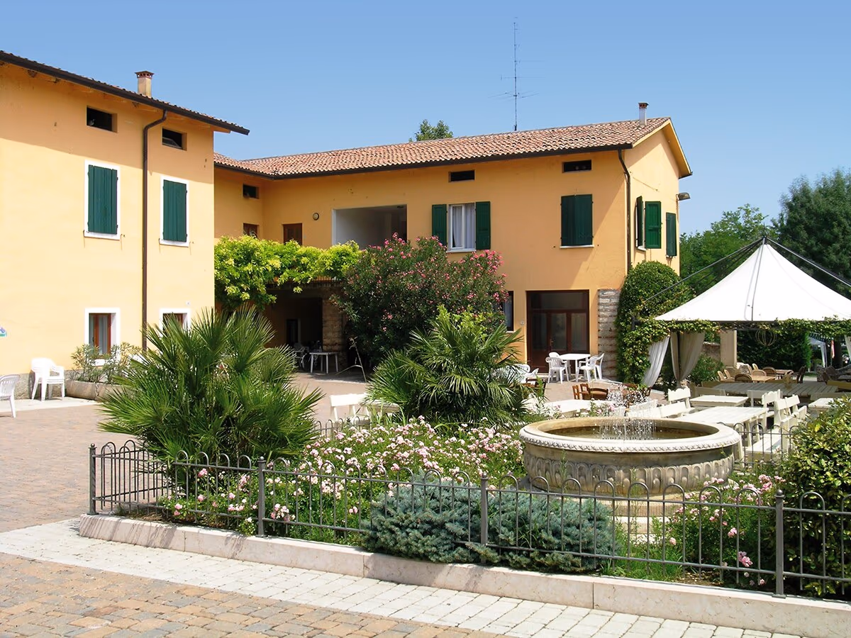 Appartementengebouw Glicine met terras en fontein in de tuin op Camping Bella Italia
