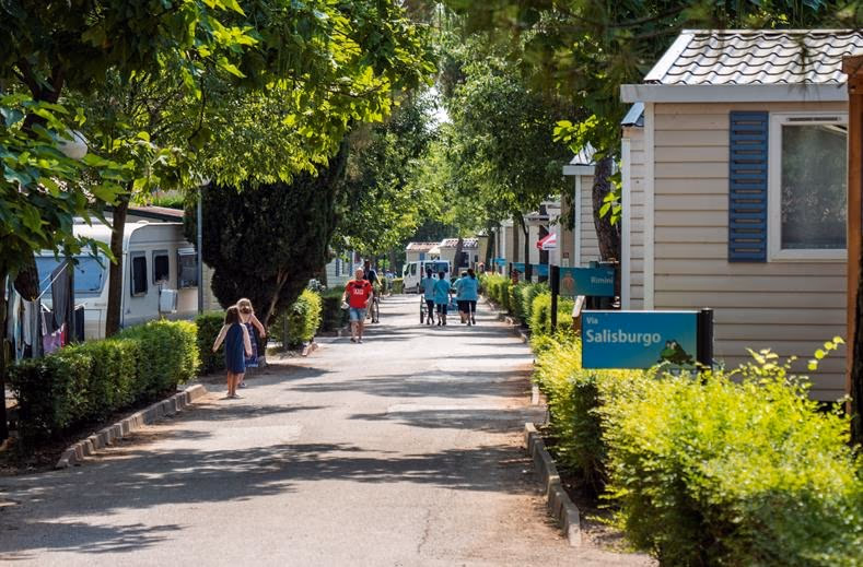 Chalets en stacaravans op een rij tussen het groen van Camping Bella Italia