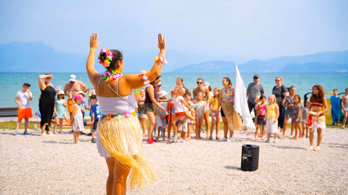 Begeleider en kinderen tijdens een dansactiviteit op het strand van Camping Bella Italia