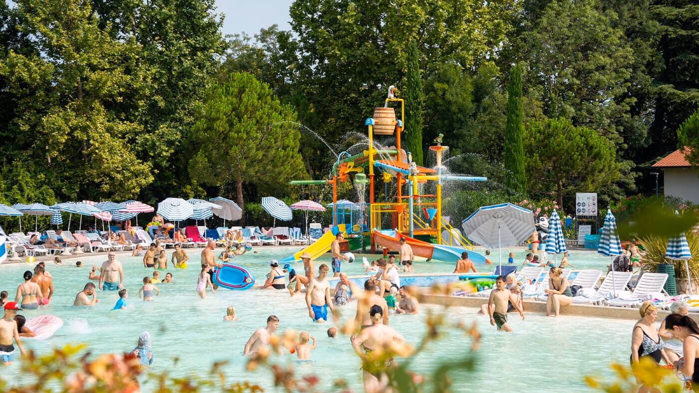 Gezinnen met jonge kinderen in het ondiepe kinderbad bij het waterspeeltoestel van Camping Bella Italia