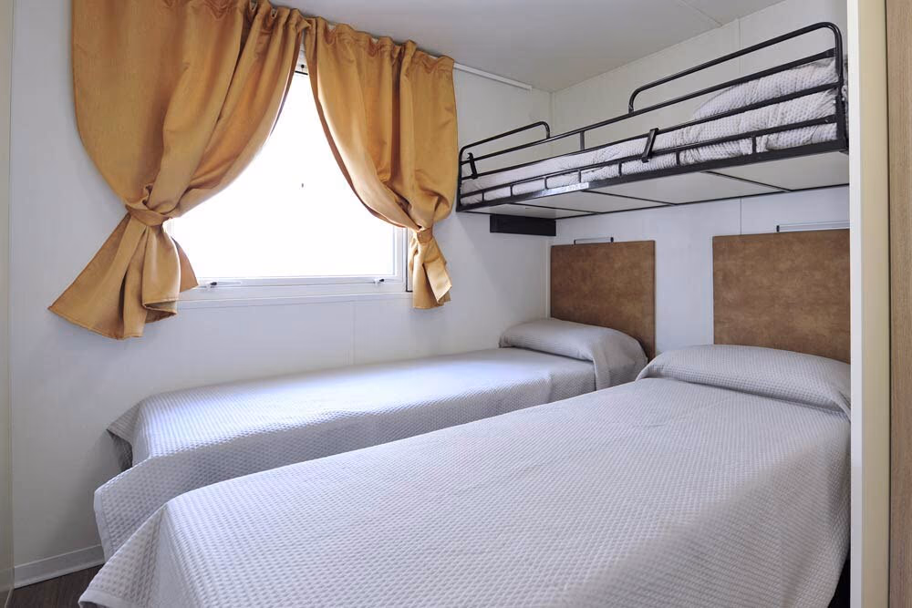 Familieslaapkamer met meerdere bedden in een mobile home van Camping Bella Italia