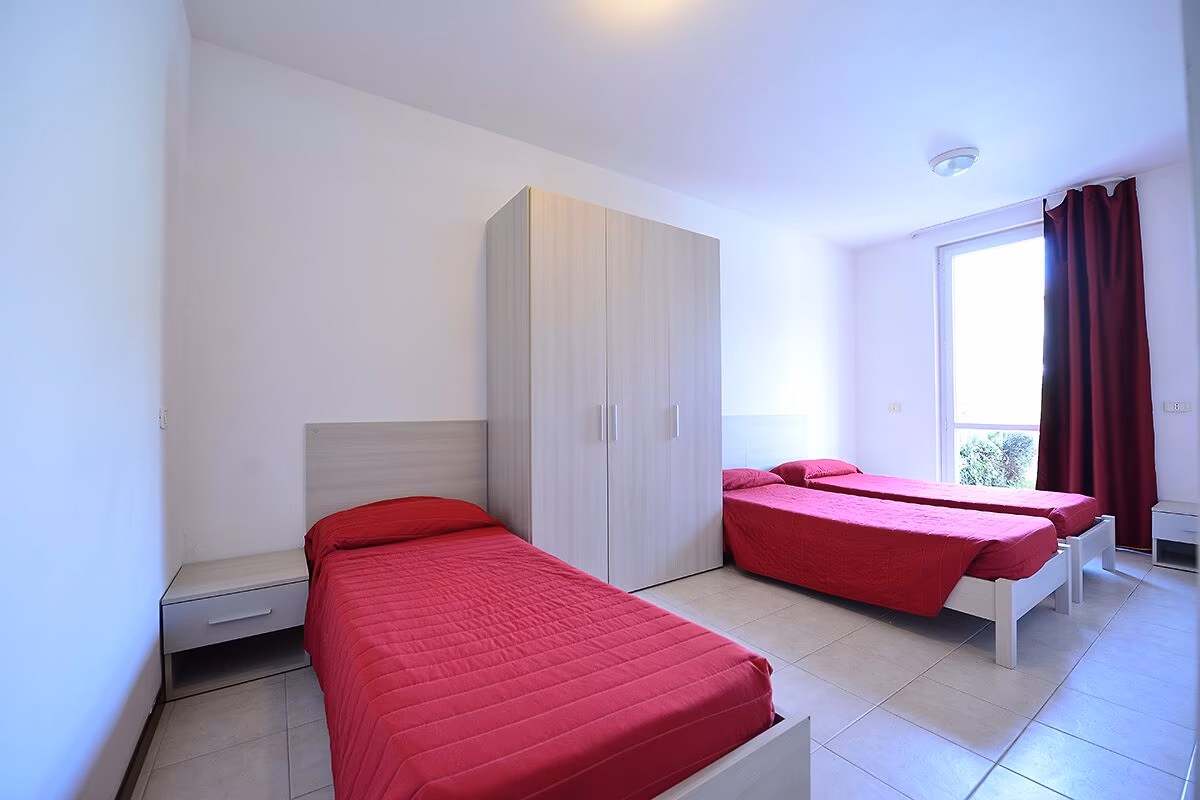 Familieslaapkamer met tweepersoonsbed en stapelbed in appartement Ibisco op Camping Bella Italia