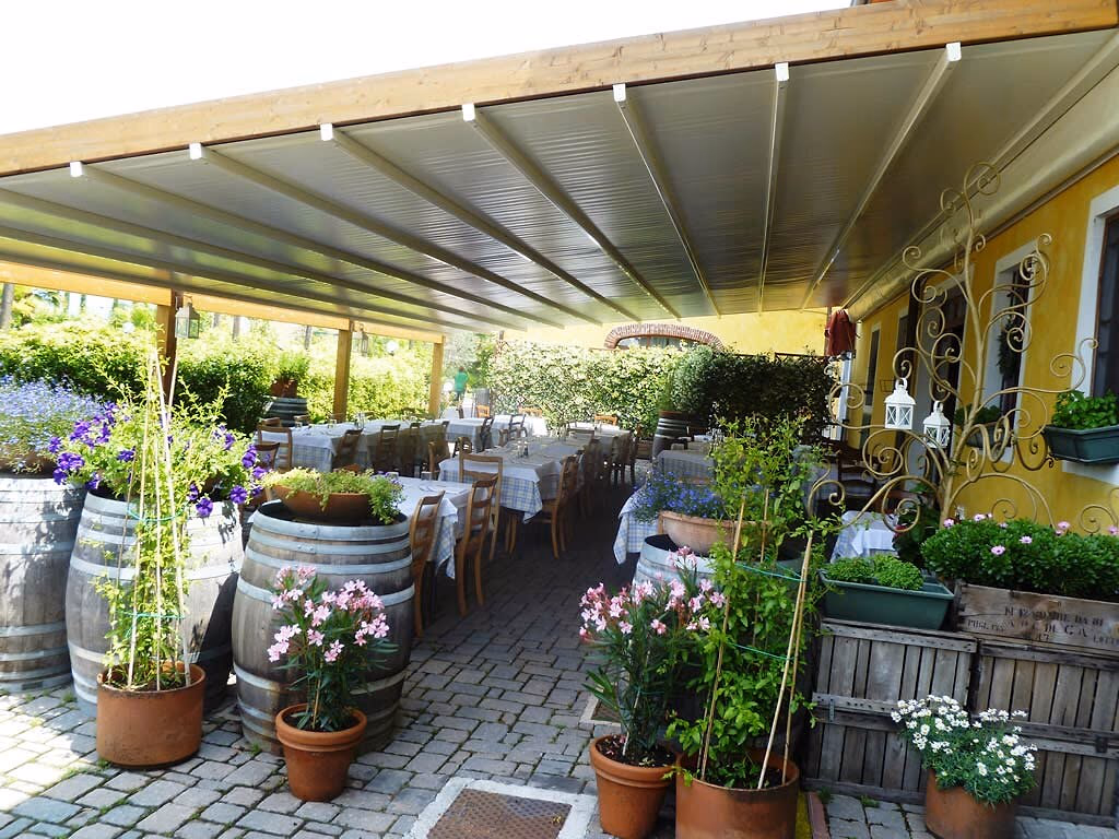Overdekt restaurantterras omringd door planten en bloemen op Camping Bella Italia