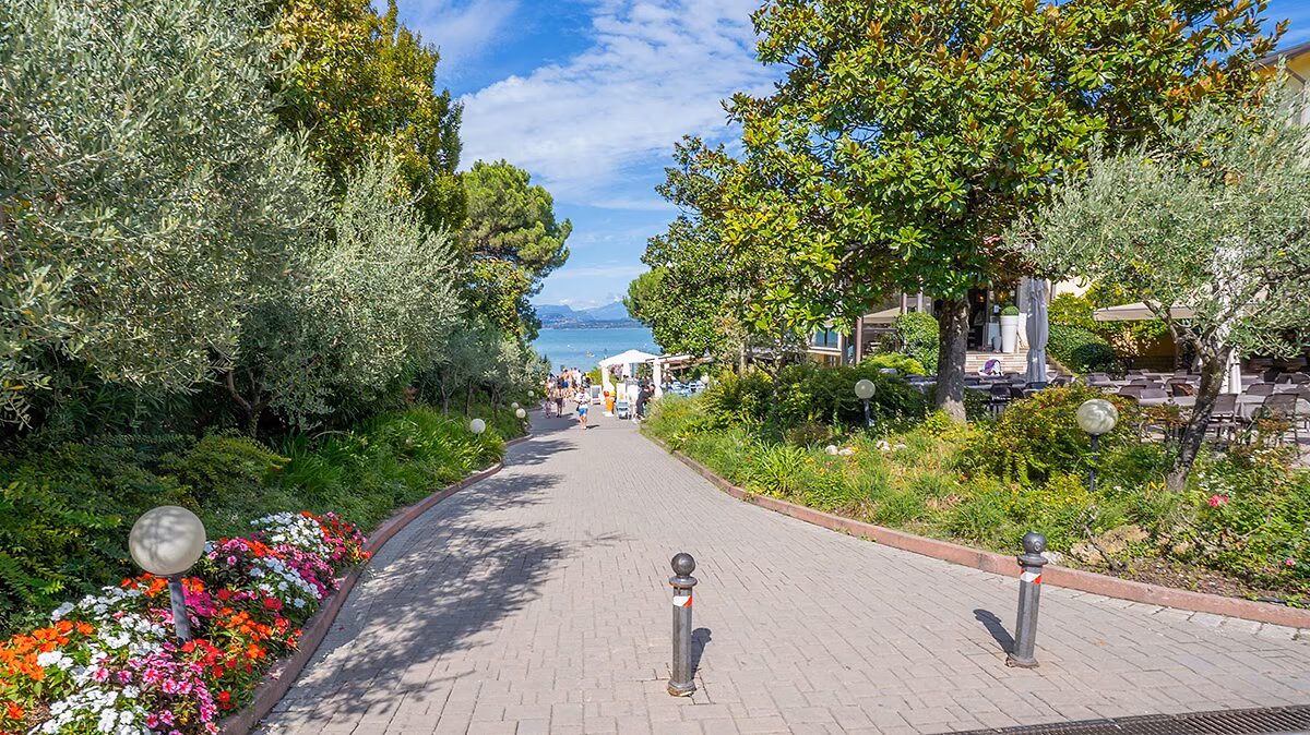 Groene laan met hoge bomen tussen de accommodaties op Camping Bella Italia