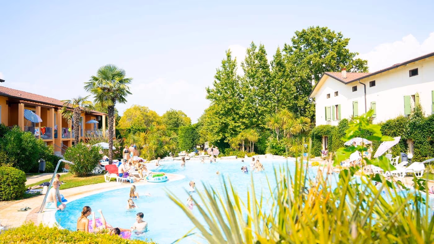 Gasten zwemmen in het grote buitenbad van het aquapark van Camping Bella Italia