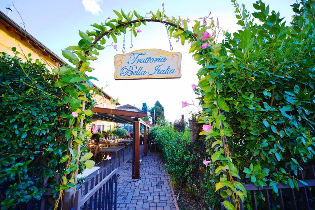 Ingang van restaurant Le Terrazze sul Lago tussen groene hagen op Camping Bella Italia