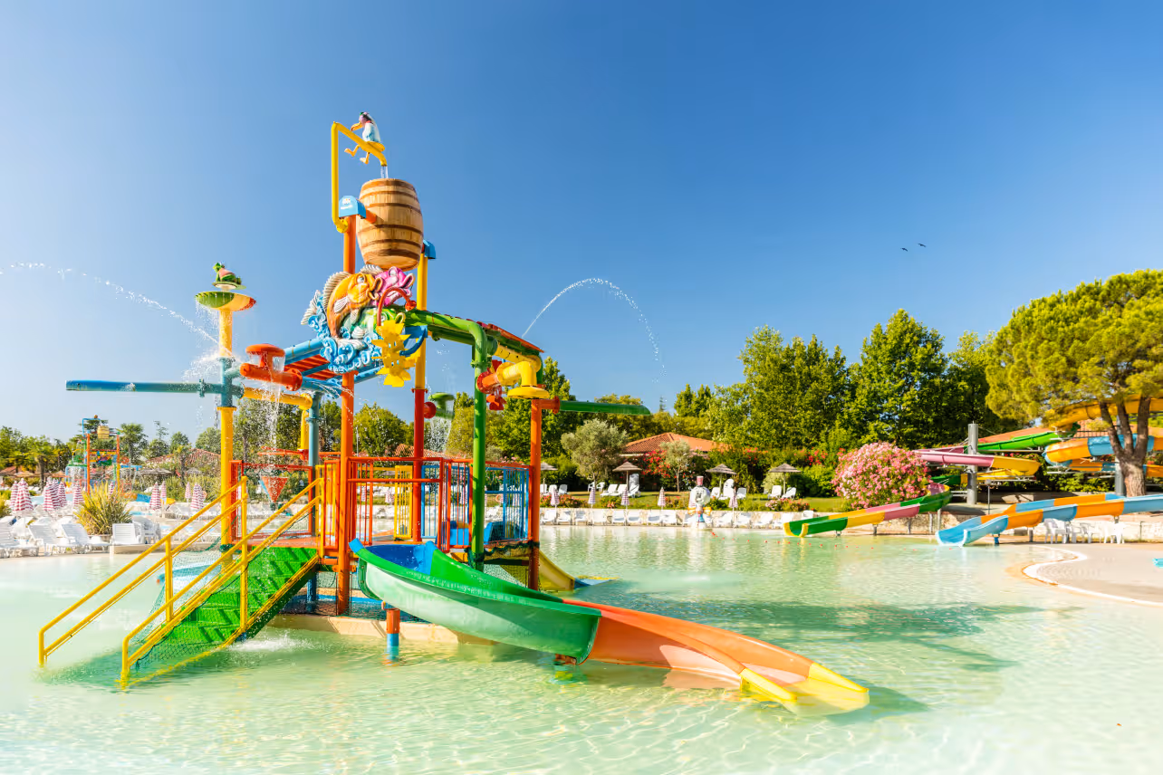 Ondiep kinderbad met kleurrijk waterspeeltoestel en glijbanen in het aquapark van Camping Bella Italia