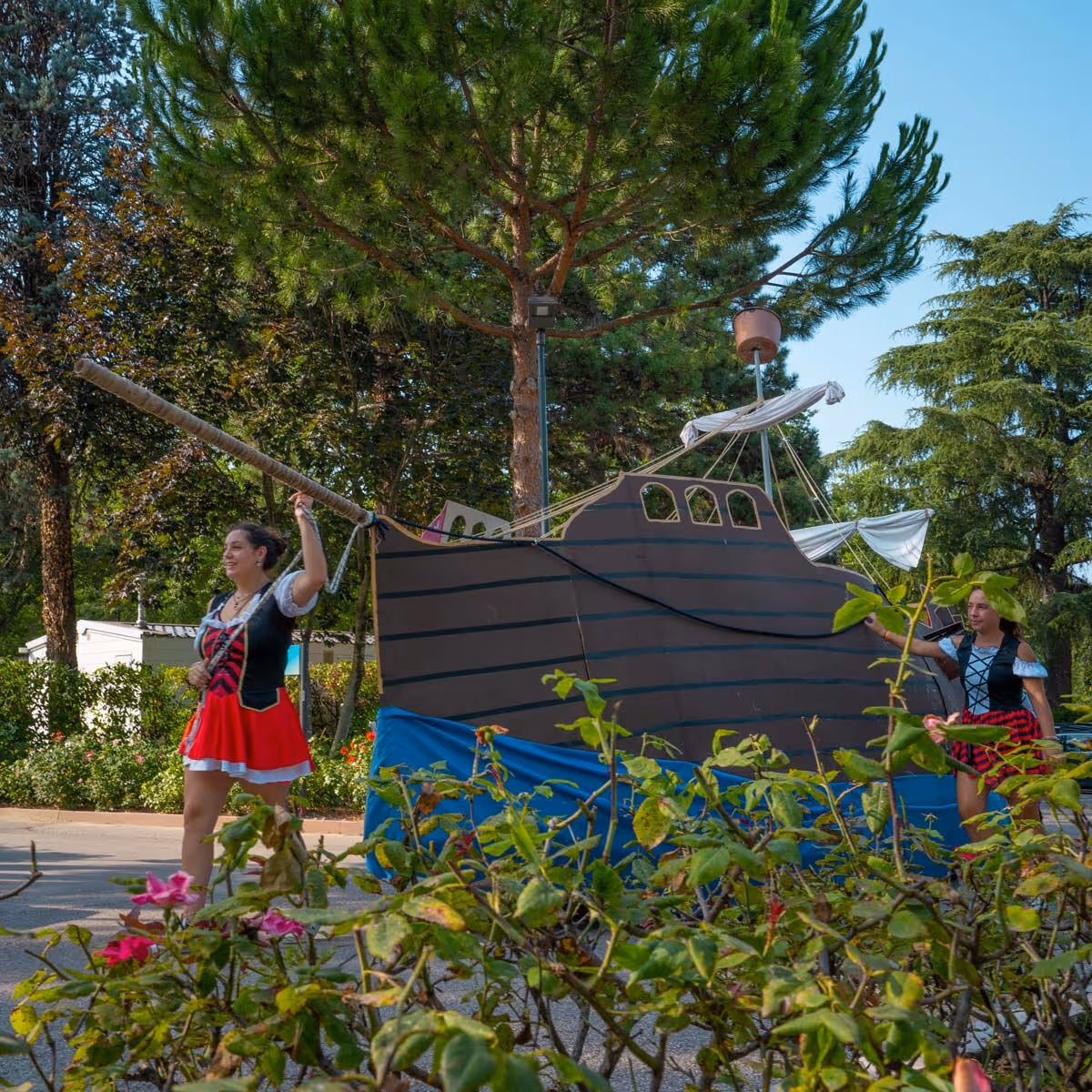 Kinderen verzamelen rond een activiteit tussen de bomen op Camping Bella Italia