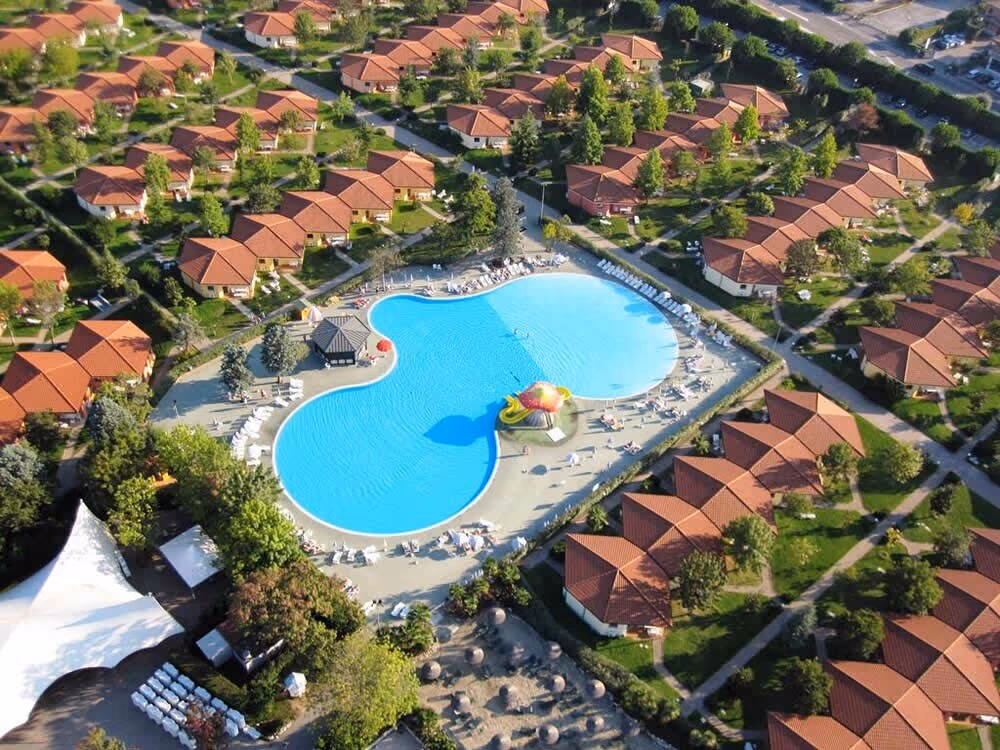 Luchtfoto van het vakantiedorp met accommodaties rond het centrale aquapark van Camping Bella Italia