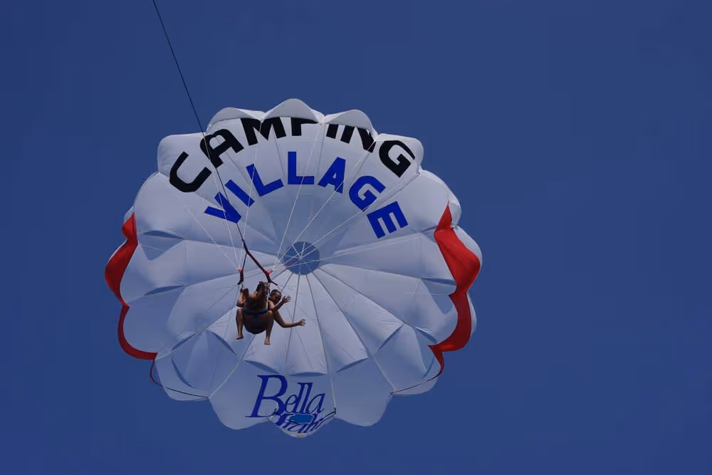 Parasailer met het logo van Camping Village Bella Italia boven het Gardameer