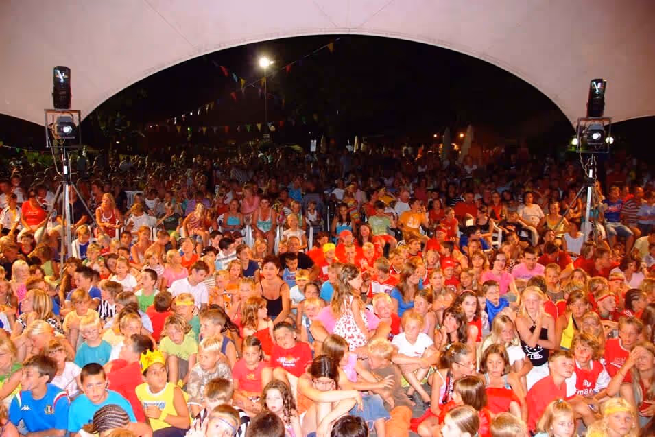 Groot publiek bij een openluchtshow in de avond op Camping Bella Italia