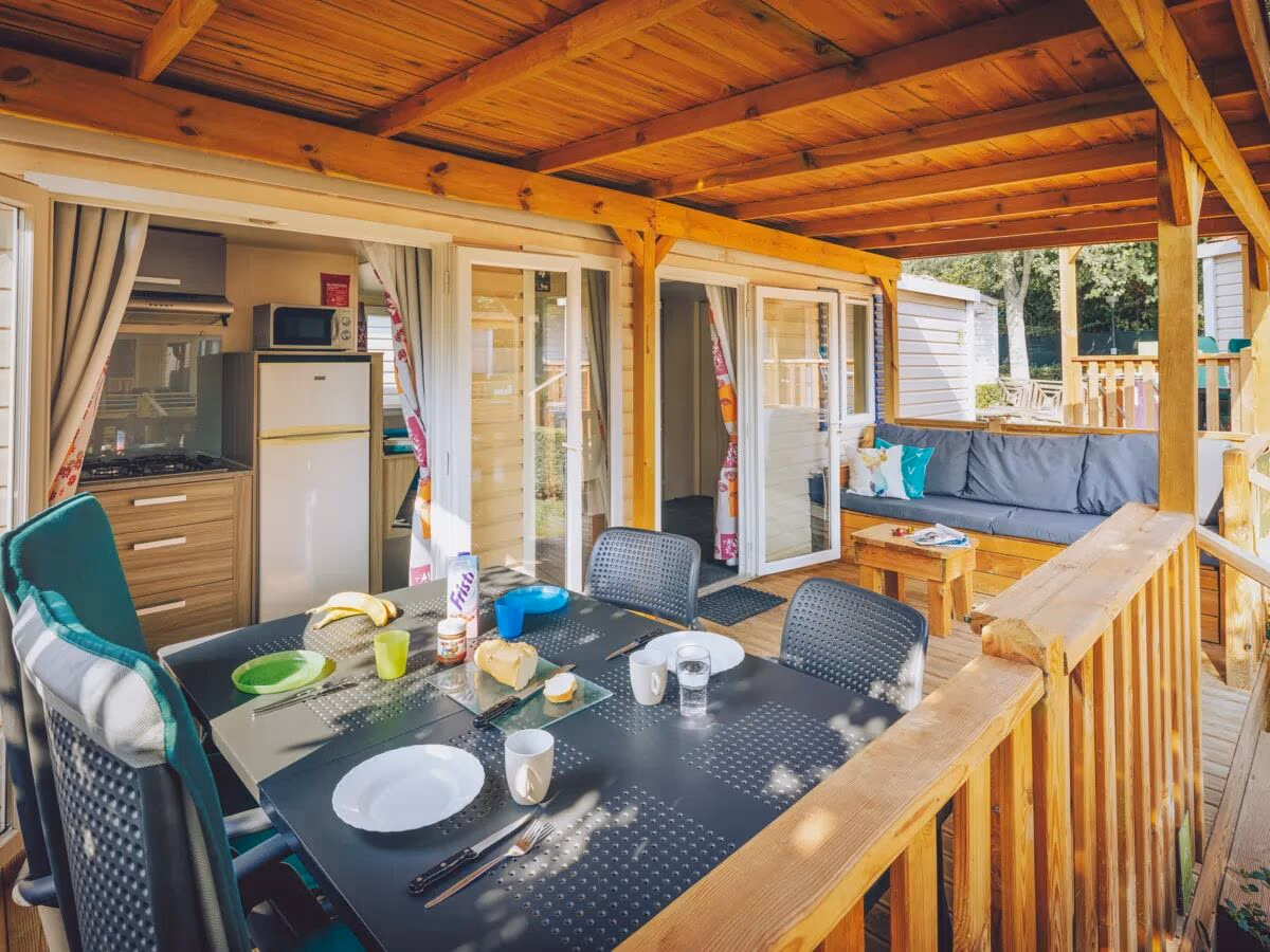Overdekte veranda met een gedekte eettafel en doorkijk naar de keuken bij een stacaravan