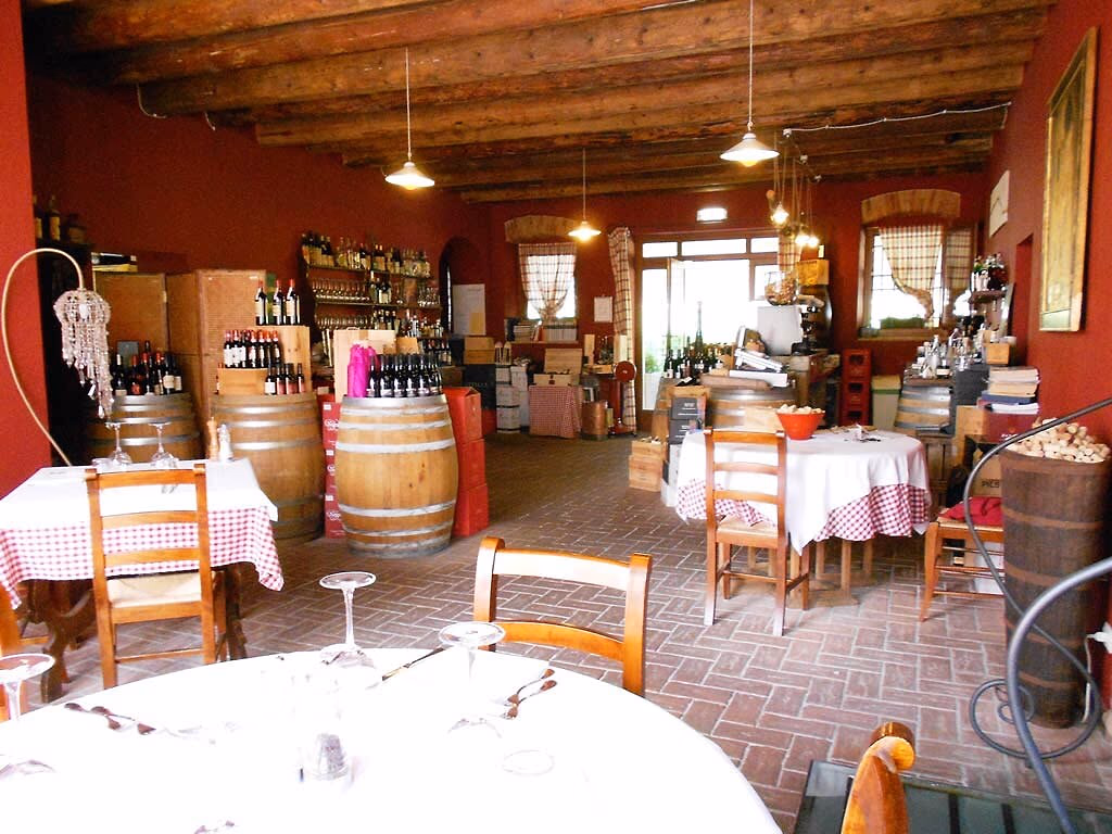 Rustiek restaurantinterieur met houten balken en gedekte tafels op Camping Bella Italia