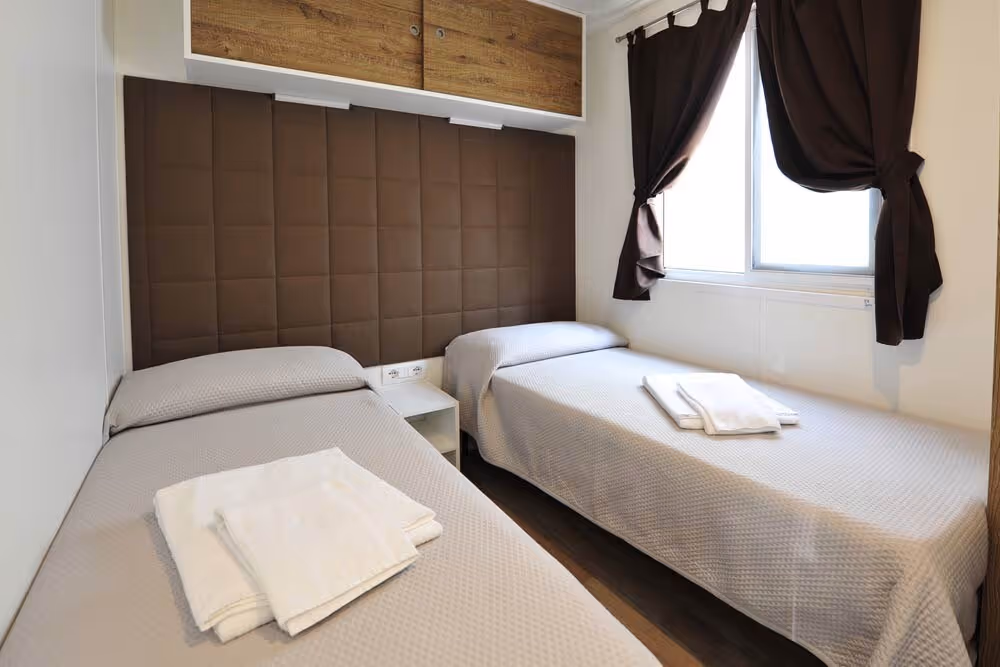 Slaapkamer met twee eenpersoonsbedden in een stacaravan op Camping Bella Italia