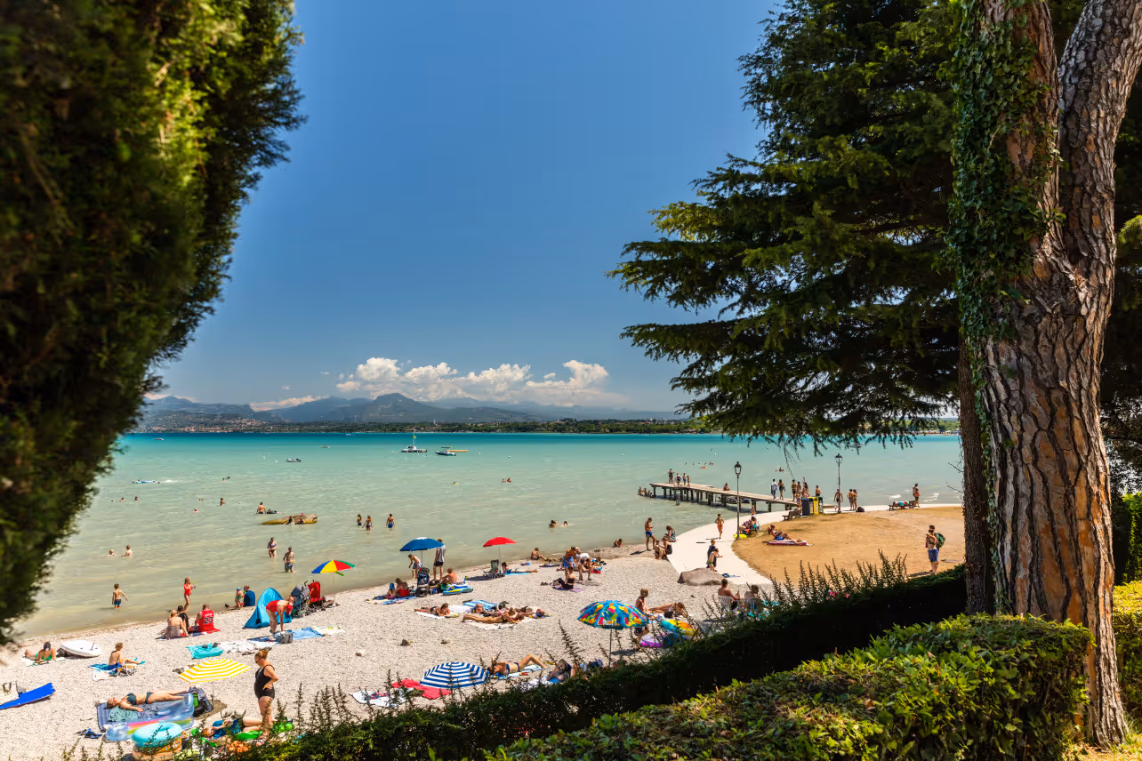 Strand van Camping Bella Italia aan het Gardameer met badende en zonnende gasten