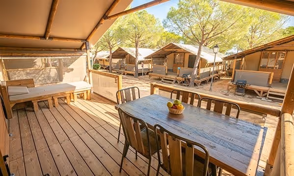 Houten terras met eettafel bij een lodgetent op Camping Bella Italia