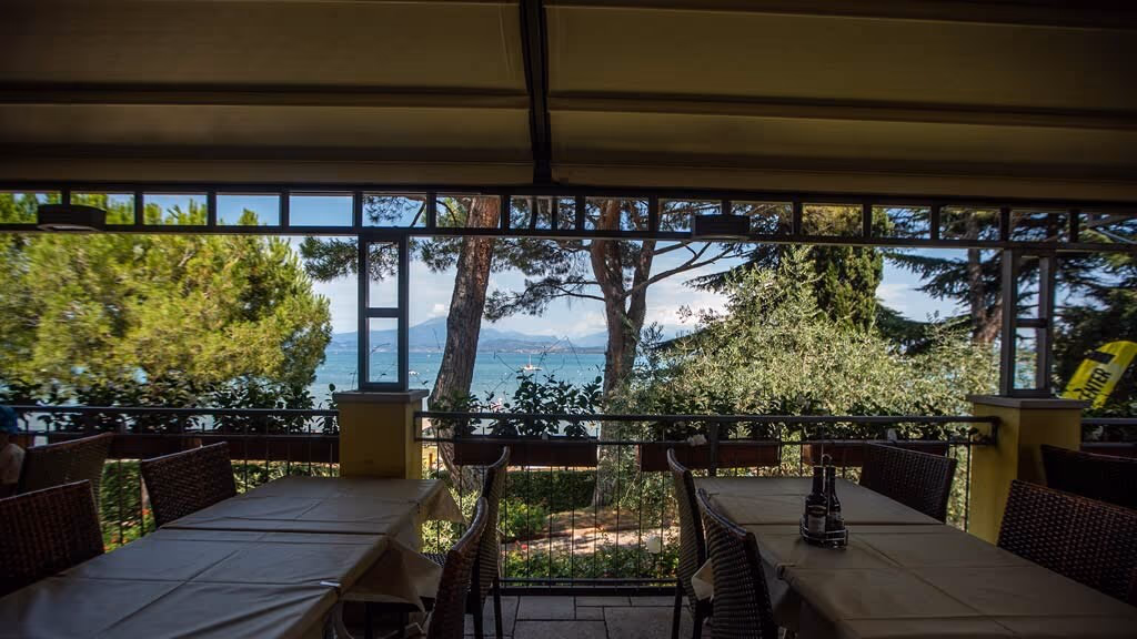 Overdekt restaurantterras met uitzicht op het Gardameer bij Camping Bella Italia