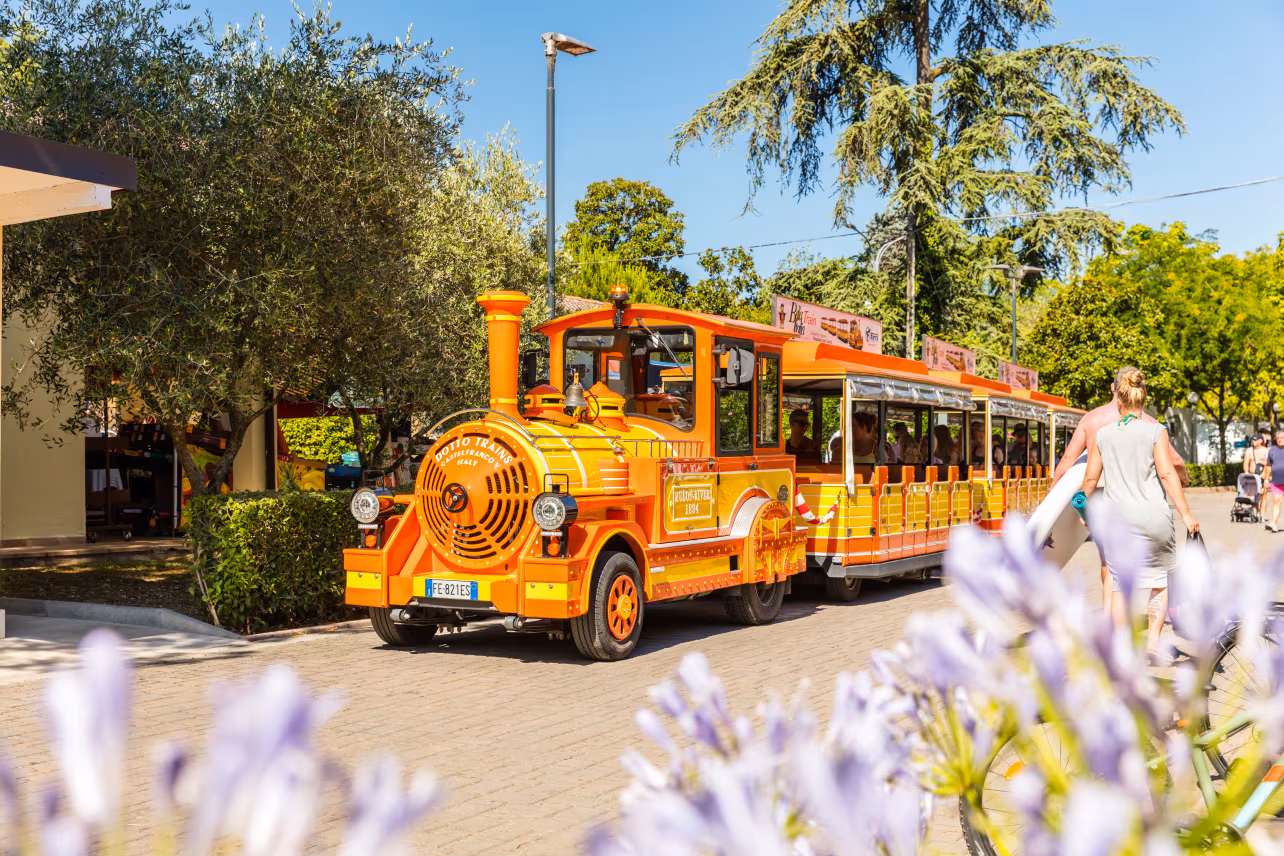 Oranje toeristentreintje rijdt over het terrein van Camping Bella Italia in Peschiera del Garda