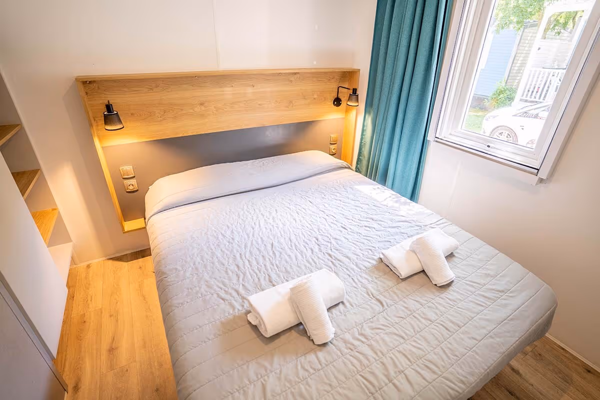 Tweepersoonsslaapkamer met kastruimte in een stacaravan van Camping Bella Italia