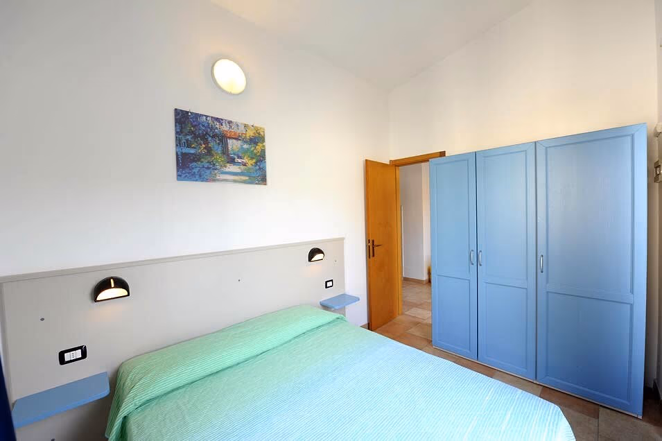 Tweepersoonsslaapkamer met blauwe kasten in appartement Verbena op Camping Bella Italia