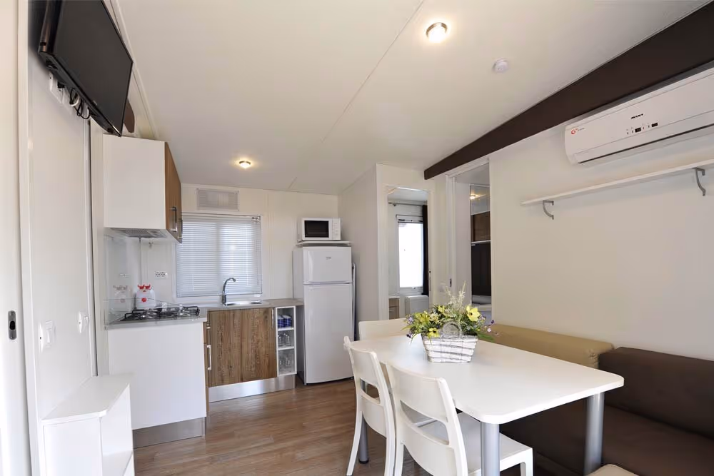 Woonkeuken met eettafel aan het raam in een stacaravan van Camping Bella Italia