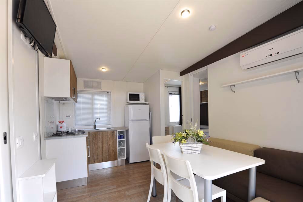 Woonkeuken met eettafel aan het raam in een stacaravan van Camping Bella Italia