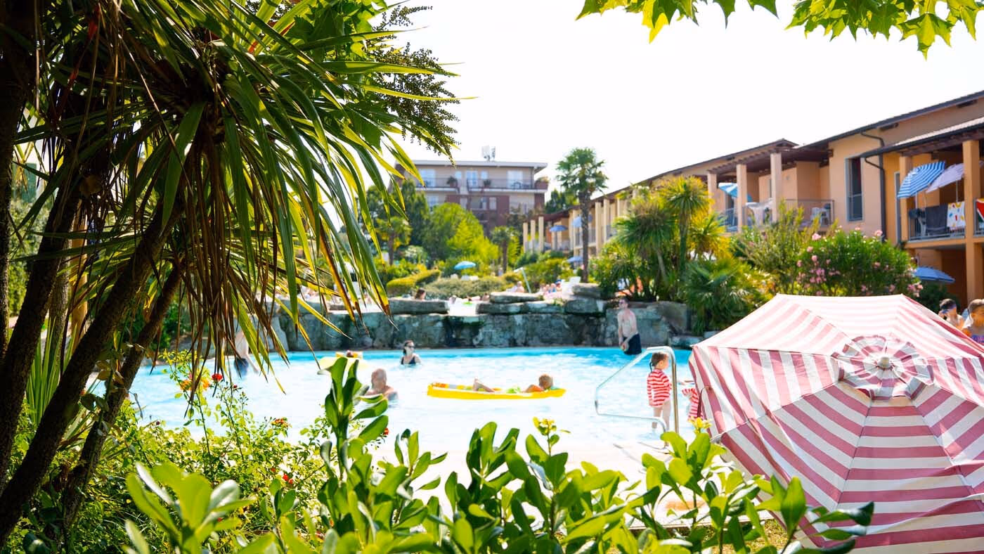 Zwembad met ligbedden en palmbomen voor de accommodaties van Camping Bella Italia