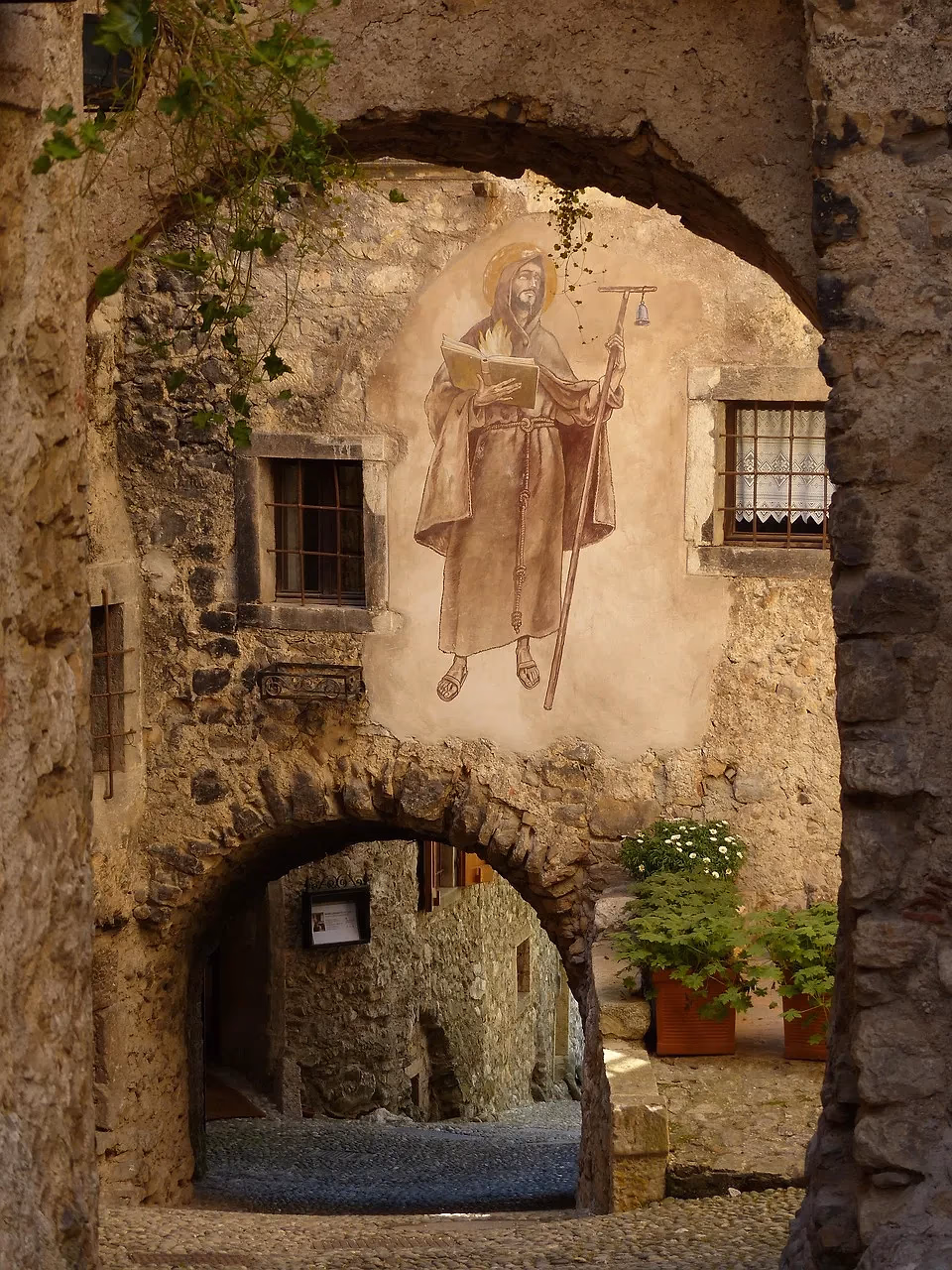 Een stenen poort met een fresco op de muur in het middeleeuwse dorp Canale di Tenno