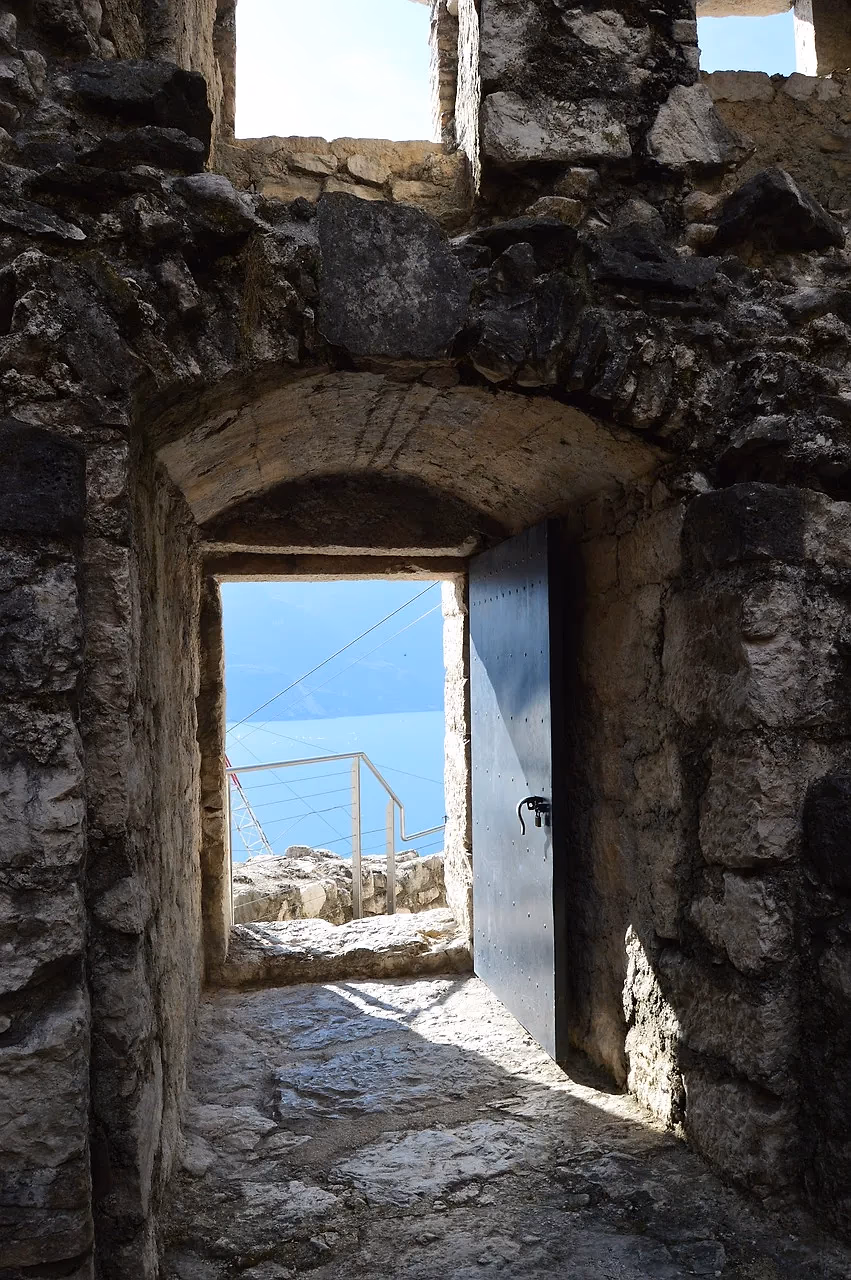 Een stenen doorgang in de Bastione boven Riva del Garda met een open deuropening naar buiten